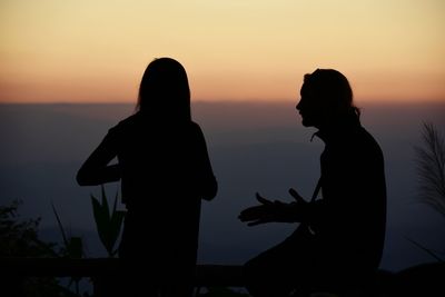 Silhouette people standing against sky during sunset