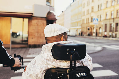 Rear view of disabled man with friend in city