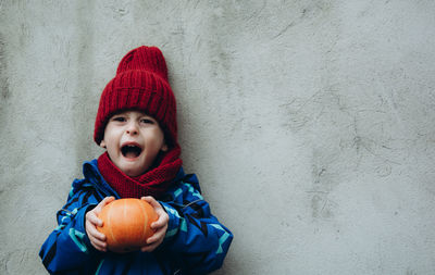 Portrait of a screaming child with a pumpkin. the kid expresses fear. halloween and holiday concept.
