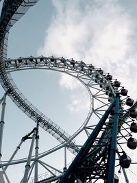 Low angle view of rollercoaster and ferris wheel against sky