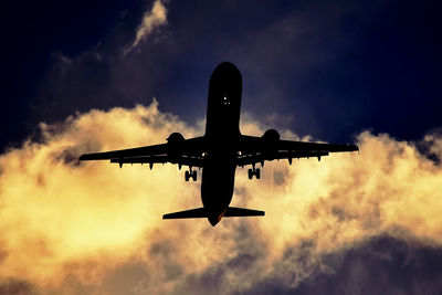 Low angle view of silhouette airplane against sky during sunset