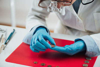 Hands of ancient coins valuation expert researching value of coins