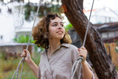 Portrait of young woman sitting on swing