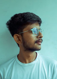 Portrait of young man looking away against wall