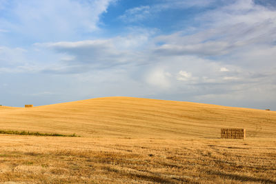 Scenic view of grassy field against cloudy sky