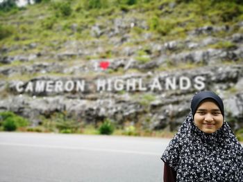 Portrait of woman standing against sign