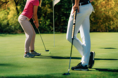 Golf couple putting on the green, unrecognizable people