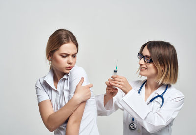 Smiling doctor vaccinating patient against white background