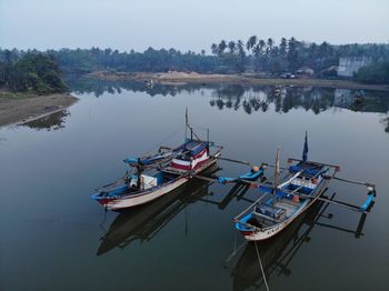 Fishing boats moored in lake against sky
