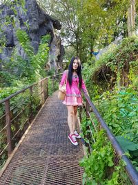 Full length portrait of woman standing against plants