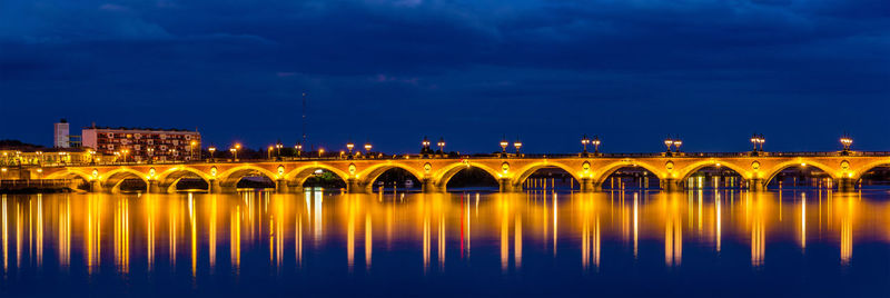 Illuminated bridge over river against sky at night