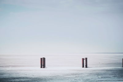 Wooden posts on beach against clear sky