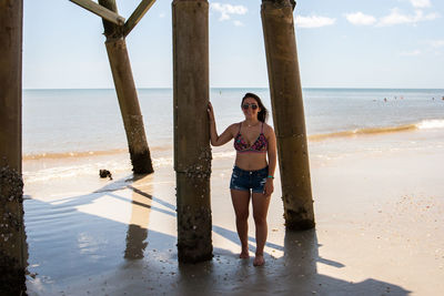 Woman standing below pier at beach