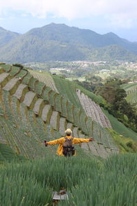 Rear view of woman walking on field against sky