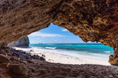 Scenic view of beach seen through cave