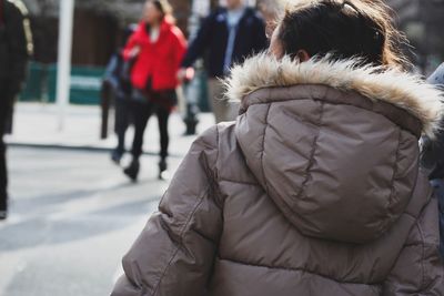 Rear view of woman wearing fur coat in city