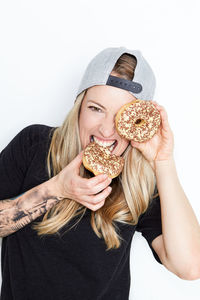 Portrait of young woman holding ice cream against white background
