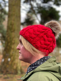 Portrait side view of woman wearing a knit hat walking in woodlands