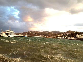 Boats in sea against cloudy sky