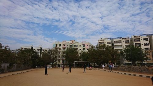 People in playground against sky in city