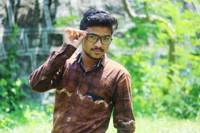 Portrait of young man standing against plants