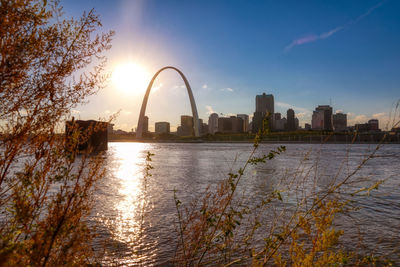 Scenic view of river by buildings against sky during sunset