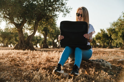 Woman using laptop while sitting at olive orchard