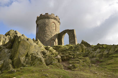 Low angle view of old ruin on rocky field against sky