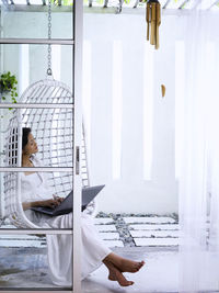 Woman using laptop while sitting in swing chair