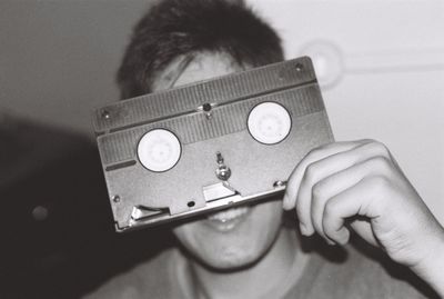 Close-up of boy holding audio cassette against face while sitting at home