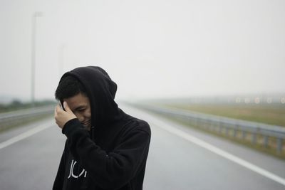 Young man standing on road against sky