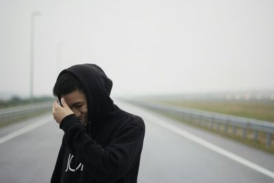 Young woman standing on road against sky