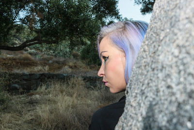 Side view of young woman against trees