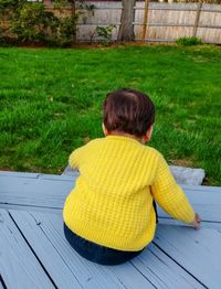 Rear view of boy sitting on grass