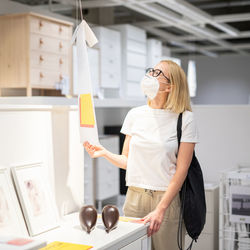 Side view of woman wearing mask standing at store