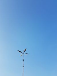 Low angle view of bird on pole against clear blue sky