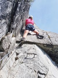 Low angle view of woman climbing on rock