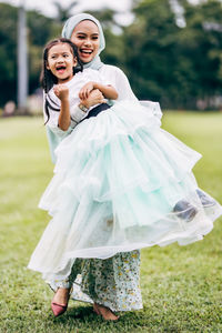 Beauiful young female teaching a beautiful child in the green field.