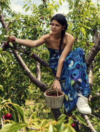 Young woman holding umbrella against plants