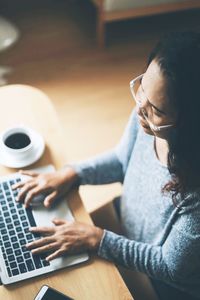 Midsection of woman working with coffee cup on table