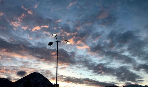Low angle view of street light against dramatic sky