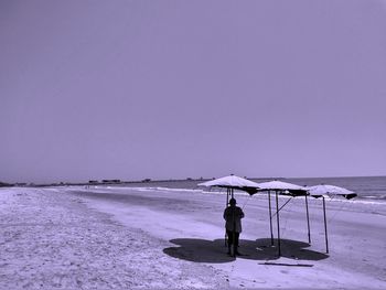 People on beach by sea against clear sky