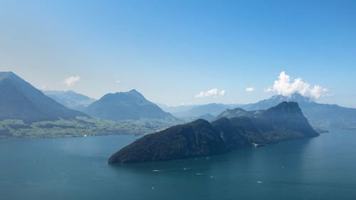 Scenic view of sea and mountains against blue sky