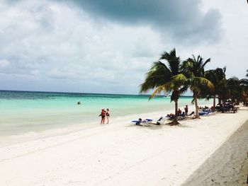 Scenic view of people on beach against sky