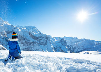 Rear view of man skiing on snowcapped mountain against sky