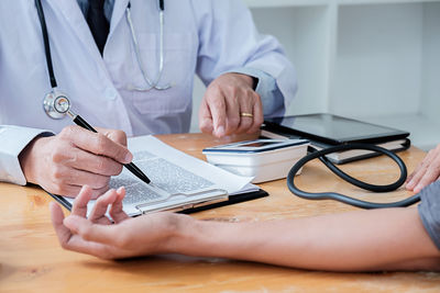 Midsection of man using smart phone on table