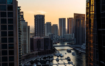 Modern buildings in city against sky during sunset