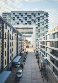 Footpath amidst buildings in city against sky