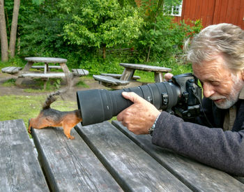 Man photographing squirrel on table