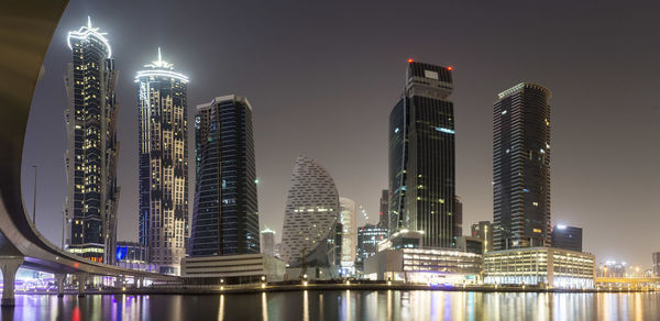 Illuminated modern buildings against sky at night